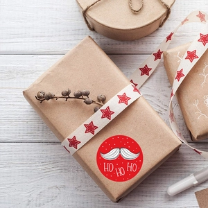 Christmas HO HO HO red round labels on a gift box with a white wood background