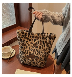 Macro detail of plush leopard print tote bag with brown faux leather trim and handle