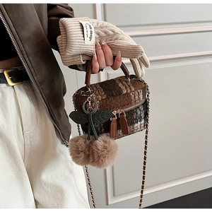 Detail van geruite tweed crossbodytas met leren handvat en een pluche kersenhanger