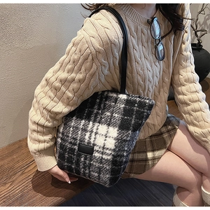 Detailed view of plush black and white checkered tote bag with black leather shoulder straps