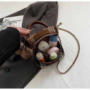 Detailopname van geruite wollen tas met opbergruimte voor cosmetica en gouden ketting