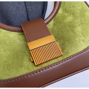 Macro view of green faux suede bag with brown leather trim and vintage gold metal lock
