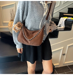 Nahaufnahme der braunen Wildleder-Schultertasche mit silberner Kette und Bärenanhänger