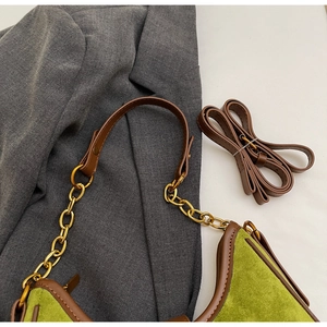 Close-up of green suede shoulder bag with brown leather trim and golden chain strap