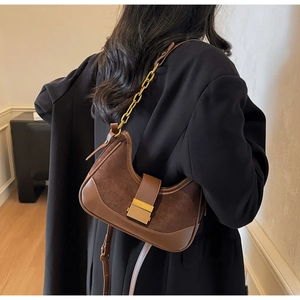 Retro brown contrast underarm bag with gold chain worn on the shoulder by a model