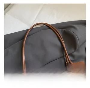 Detail of slim rounded handle and neat stitching on vintage brown suede tote bag