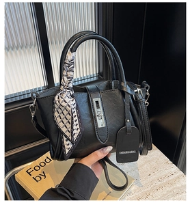 Detail of black bucket bag with silver hardware and geometric silk scarf handle decoration