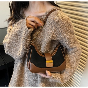 Detail view of the brown suede and black leather patchwork crescent shoulder bag