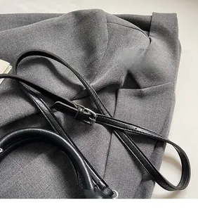 Detail of adjustable black leather shoulder strap with silver buckle on a bucket bag