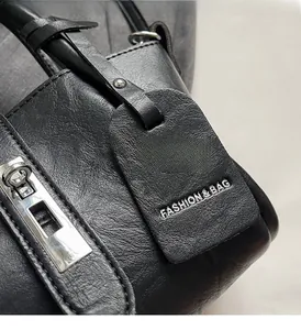 Detail of black leather bucket bag with silver metal clasp and fashion tag