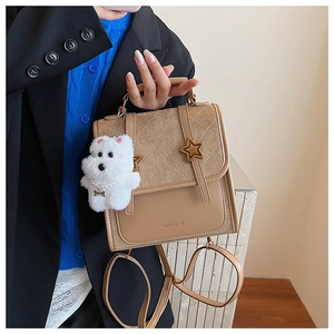 Detail view of beige fashion backpack with quilted flap and cute plush dog pendant