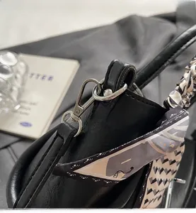 Detail of black leather bucket bag with silver hardware and silk scarf handle