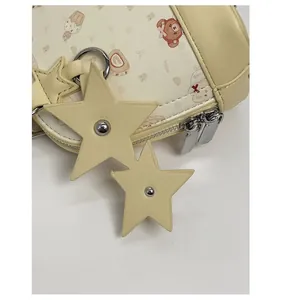 Detail of cream PU shell bag featuring cute cartoon prints and twin star charms with silver studs