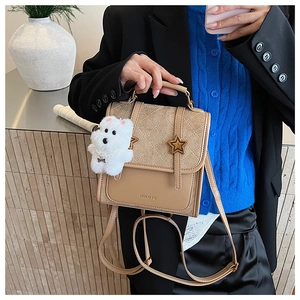 Detail of khaki quilted backpack with star buckles and a white plush dog charm accessory
