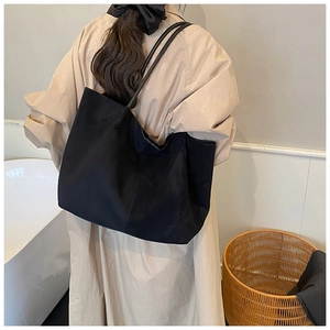 Detail shot of a black suede minimalist tote bag showing large capacity and shoulder straps