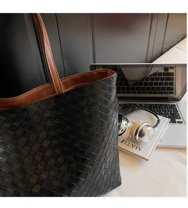 Close-up of black woven leather tote bag texture with interior brown lining detail