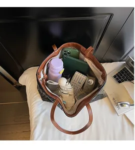 Top view of spacious black woven tote bag interior with umbrella, water bottle, and phone