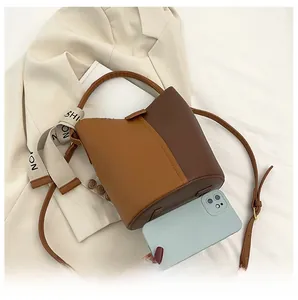 Vue détaillée d'un sac seau bicolore marron avec foulard et comparaison de taille réelle