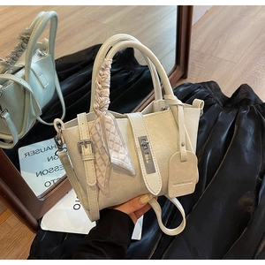 Détail du sac seau crème avec poignée en foulard de soie et fermoir rotatif en métal