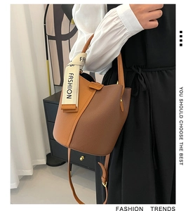 Détail d'un sac seau en cuir marron avec un ruban de soie décoratif sur la poignée