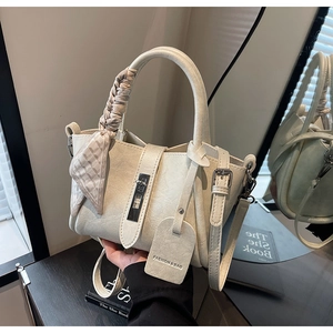 Détail du sac seau en cuir crème avec poignée en foulard et fermoir métallique