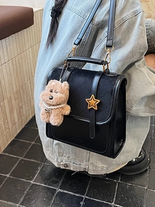 Black quilted crossbody bag with star clasp and bear charm worn with denim jacket