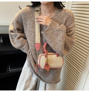Detail van beige canvas crossbodytas met roze lederen bies en brede schouderband op het model