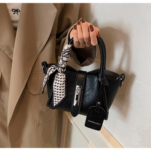 Détail du sac seau noir mat avec poignée en foulard de soie à motifs et fermoir argent