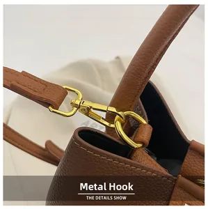 Gros plan du crochet doré sur un sac seau marron en cuir avec grain de litchi