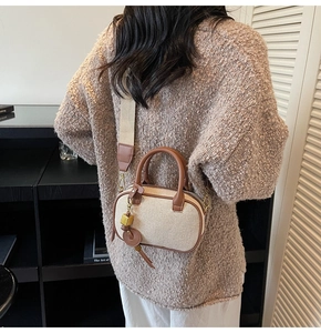 Detail van Boston-tas van beige stof met bruine lederen bies en afneembare schouderband