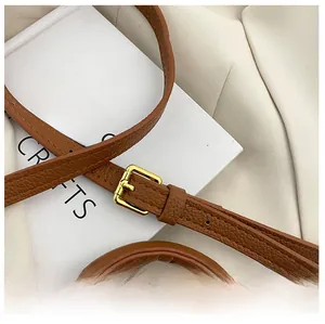 Détail de la bandoulière réglable en cuir marron avec boucle en métal doré raffiné