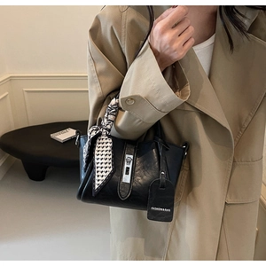 Détail du sac seau en cuir noir avec foulard géométrique et fermoir argenté chic