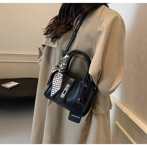 Détail du sac seau en cuir grainé noir avec fermoir argenté et foulard à damier décoratif