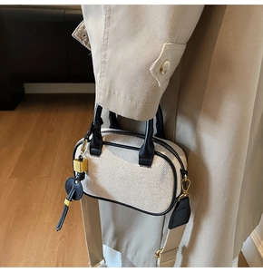 Detail van een chique geweven mini crossbodytas met zwarte lederen bies en goud
