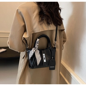 Detail of black leather bucket bag with geometric silk scarf handle and metal clasp