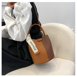Détail du sac seau bicolore en cuir grainé avec bandoulière à logo FASHION