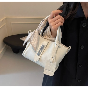Détail du sac seau crème avec fermoir argenté et poignée ornée d'un foulard en soie à carreaux