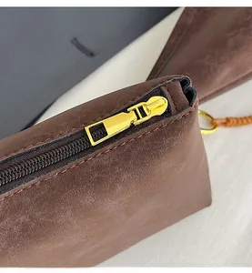 Close-up of smooth gold-tone zipper and vintage brown leather texture on a tote bag