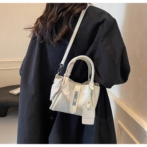 Vue détaillée du sac seau crème en cuir grainé avec un foulard en soie à carreaux chic