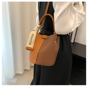Détail du sac seau bicolore en cuir grainé avec ruban imprimé et bandoulière amovible