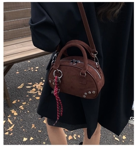 Détail du sac Boston en daim marron foncé avec rivets argentés et charme tissé en automne