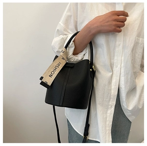 Détail d'un sac seau en cuir grainé noir avec ruban décoratif et anse ronde