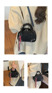 Détail du sac Boston en daim noir avec clous argentés et foulard en soie à carreaux