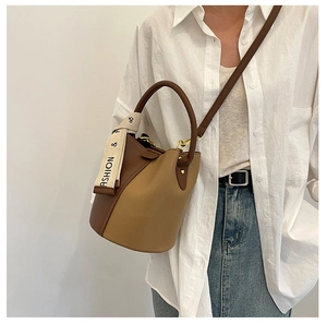 Sac seau bicolore à texture de litchi porté par un mannequin en tenue décontractée