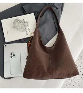 Detail of vintage brown leather tote bag with wooden bead tassel in a lifestyle setting