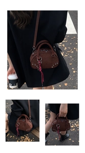 Détail du sac bandoulière en daim marron avec clous argentés et tirette de zip logo