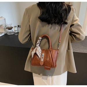 Sac seau en cuir marron avec foulard en soie porté par un mannequin dans un café