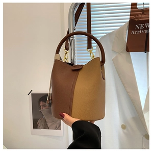 Détail d'un sac seau bicolore avec texture litchi et finitions en métal doré