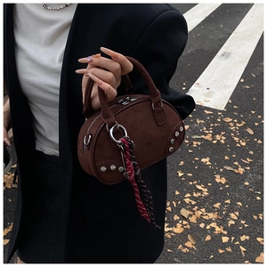 Détail du sac bowling en daim marron foncé avec rivets argentés et accessoire foulard écossais