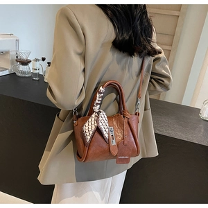 Détail d'un sac seau en cuir marron avec foulard en soie et boucle argentée élégante